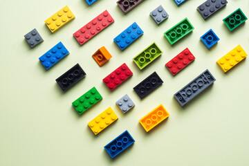 various colorful plastic toy bricks stackable blocks on yellow panoramic background, childhood education construction concept,