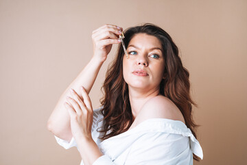 Beauty portrait of body positive woman with dark hair with pipette with organic oil on clean fresh...