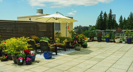 Patio furniture, umbrella and hummingbird feeder on BC rooftop patio garden, summer.