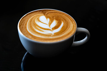 Lette are coffee in white cup with shadow on dark background