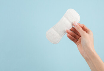 Pads in female hand on a blue background. Menstruation, critical days, feminine hygiene