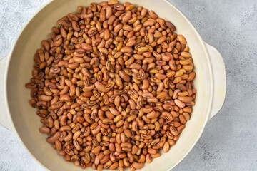 yard long bean seeds in a white cup, also known as asparagus bean or snake bean or chinese long bean, protein rich vegetable seeds on white textured surface, taken from above with copy space