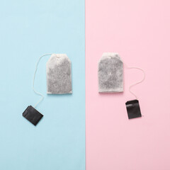 Two tea bags with blank black labels on a pink blue background. Top view