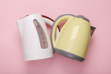 Two Plastic electric kettles on pink pastel background. Top view