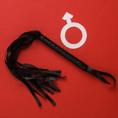 Leather sex shop whip with a male gender symbol on a red background. Domination
