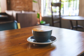 Closeup image of a cup of hot latte coffee with latte art on wooden table in cafe
