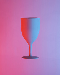 Plastic glass floating in the air, isolated in blue-red neon gradient light. Levitating objects. Minimal concept