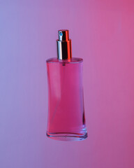 Pink perfume bottle floating in the air, isolated in blue-red neon gradient light. Levitating objects. Minimal fashion concept