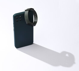 Aesthetic shot of a modern smartphone and smart bracelet with a long shadow