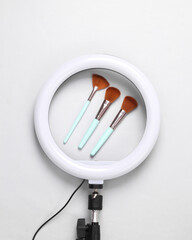 Led ring lamp with makeup brushes on a gray background. Gear for Beauty blogging and vlogging. Top view
