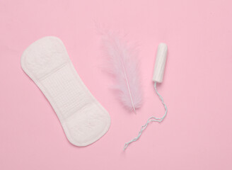 Women's intimate hygiene. Pad with tampon and soft feather on pink background