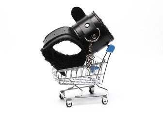 Shopping cart with bdsm leather handcuffs on a white background. Sex shop
