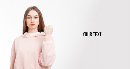 Young serious woman showing fist isolated on white background. Symbol of feminine power, femenism