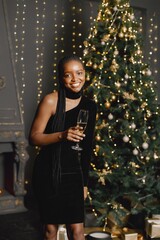 Portrait of black woman in elegant dress standing near christmas tree