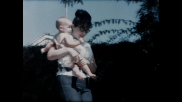 Mom and Baby 1965 - A mother holds her infant daughter as she walks outside in 1965.