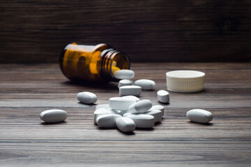 medicine pill tablet with spilled bottle on wooden table 