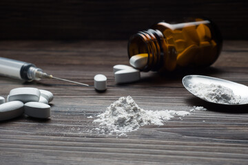 Drugs set - powder and pills and syringe on wooden background