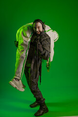 a soldier in a studio on a green background with a medic or scientist in a white protective suit. a man in military uniform rifle or machine gun carries a person in chemical protection on his shoulder