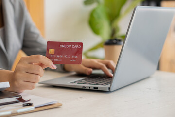 Businesswoman entering credit card number on laptop from holding credit card using simple interbank payment immediately to buy in the online store