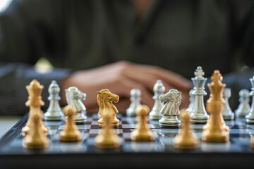 Businessman planning strategy with chess pieces on old wooden table A man is embracing the idea of playing chess at the conceptual table of sporting events and business.
