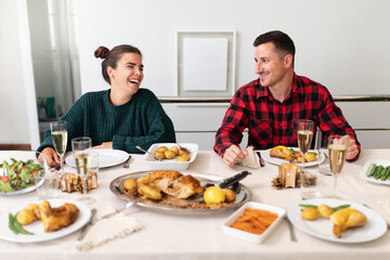 Fototapeta na wymiar Happy, smiling young caucasian couple in love during Christmas family gathering. Christmas meal.