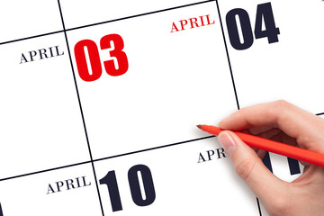 A hand holding a red pen and pointing on the calendar date April 3. Red calendar date, copy space,...