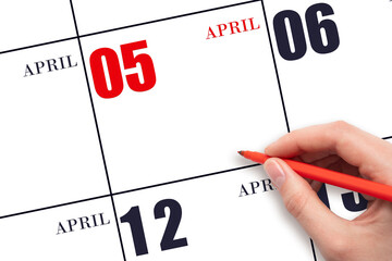 A hand holding a red pen and pointing on the calendar date April 5. Red calendar date, copy space,...