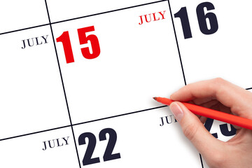 A hand holding a red pen and pointing on the calendar date July 15. Red calendar date, copy space,...