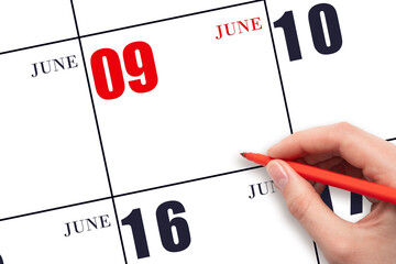 A hand holding a red pen and pointing on the calendar date June 9. Red calendar date, copy space,...