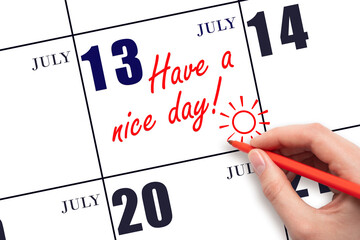 The hand writing the text Have a nice day and drawing the sun on the calendar date July 13