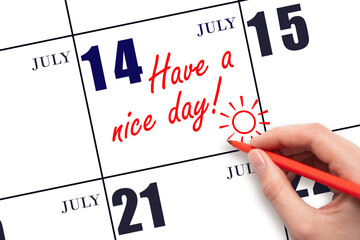 The hand writing the text Have a nice day and drawing the sun on the calendar date July 14