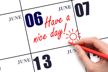 The hand writing the text Have a nice day and drawing the sun on the calendar date June 6