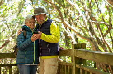 Lovely caucasian senior couple with backpack hiking together in the woods enjoying healthy...