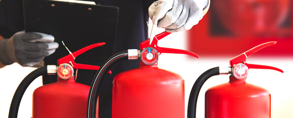 Close up fire extinguisher and firefighter checking pressure gauge level for protection and prevent and safety rescue and use of equipment on fire training concept.