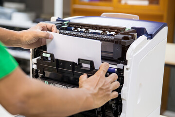 Technician hand open cover photocopier or photocopy to fix copier paper jam and replace ink cartridges for scanning fax or copy document in office workplace.