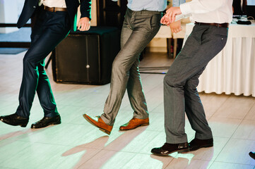 Young men in suit dancing, having fun at a party. Stylish outlook, successful businessman, happy, expressing true positive emotions, funny. A place for text. Bottom view of shoes and floor. - Powered by Adobe