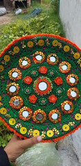Decorated round plate with colourful thread and mirrors.