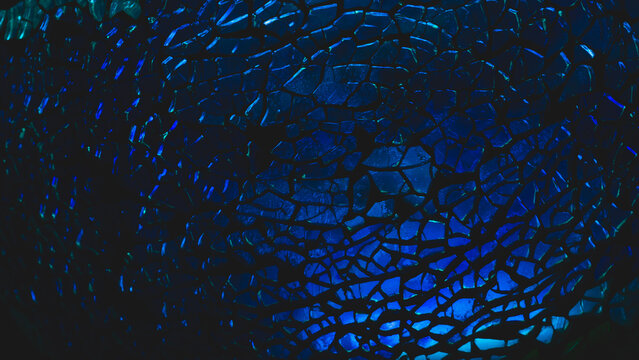 Shattered transparent glass pattern in the dark. abstract cracked background. blue splinters