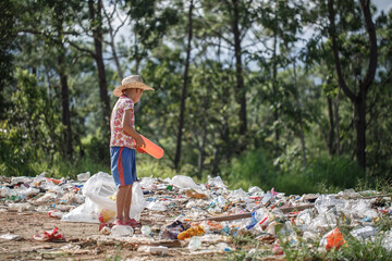 A poor boy collecting garbage waste from a landfill site. Concept of livelihood of poor...