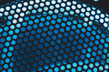 Blue light shines through the ventilation grid holes of computer air cooling system. abstract background