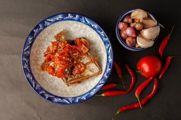 Tomato salted fish. Onions, tomatoes and chilies. black background.