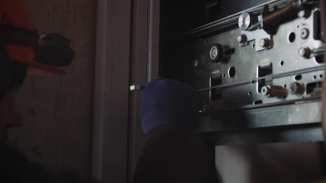 Employee adjusts mechanism of contemporary elevator in building closeup. Preparation for safe launch of equipment