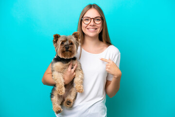 Young Lithuanian woman holding a dog isolated on blue background with surprise facial expression