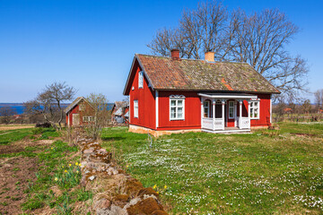 Red idyllic cottage with blooming garden in spring