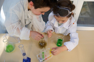 Overhead view of smart school kids, wearing white lab coat, learning Chemistry in the school...
