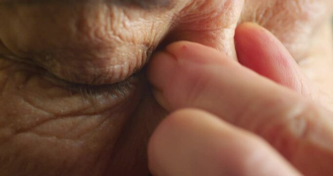 Blue eyes, stress and senior woman with headache, depression and mental health anxiety. Zoom on face vision, skin and hand of retirement elderly with burnout, looking sad and thinking about wellness
