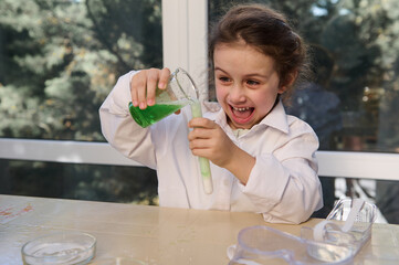 Mischievous Caucasian little girl, inspired scientist chemist wearing a white lab coat, conducting...