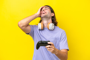 Young handsome caucasian man playing with a video game controller over isolated on yellow background smiling a lot © luismolinero