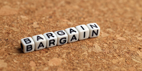 Closeup of word on plastic cube on wooden desk background concept - bargain