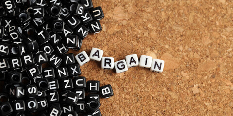 Closeup of word on plastic cube on wooden desk background concept - bargain